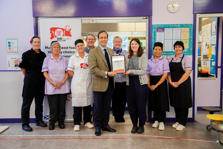 Sarah Gowanlock presents Aberdeen City's Cllr Martin Greig with the Food for Life Served Here Bronze award certificate at Culter Primary School